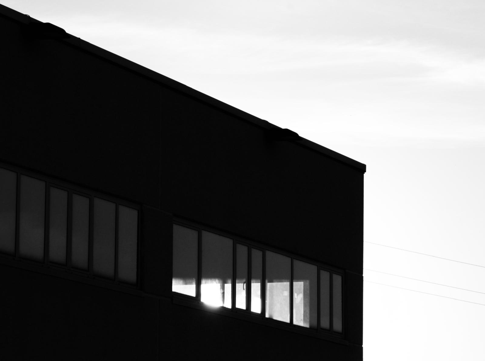 Black building facade against a bright sky