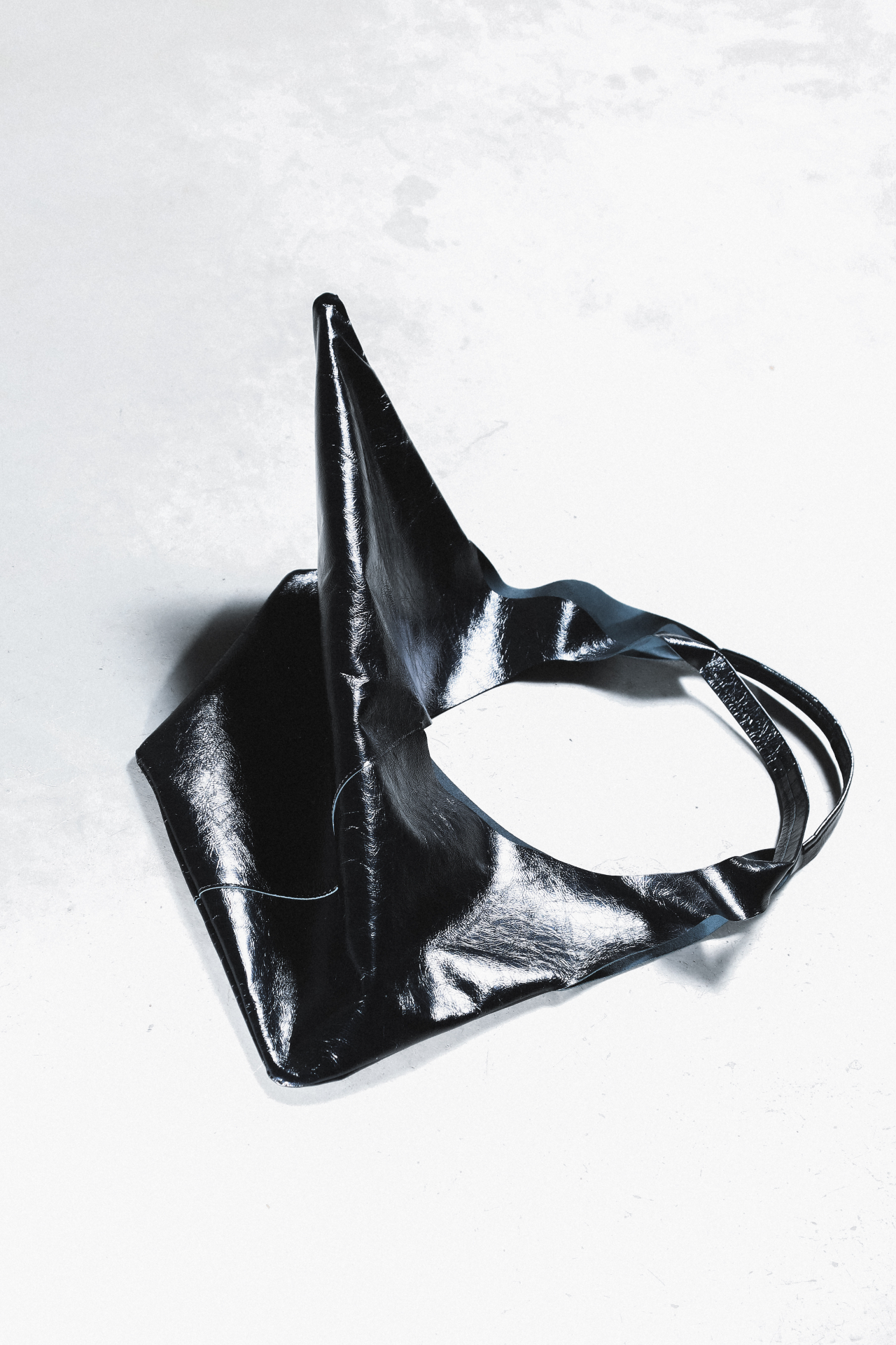 Black folded leather bag on a pale stone surface