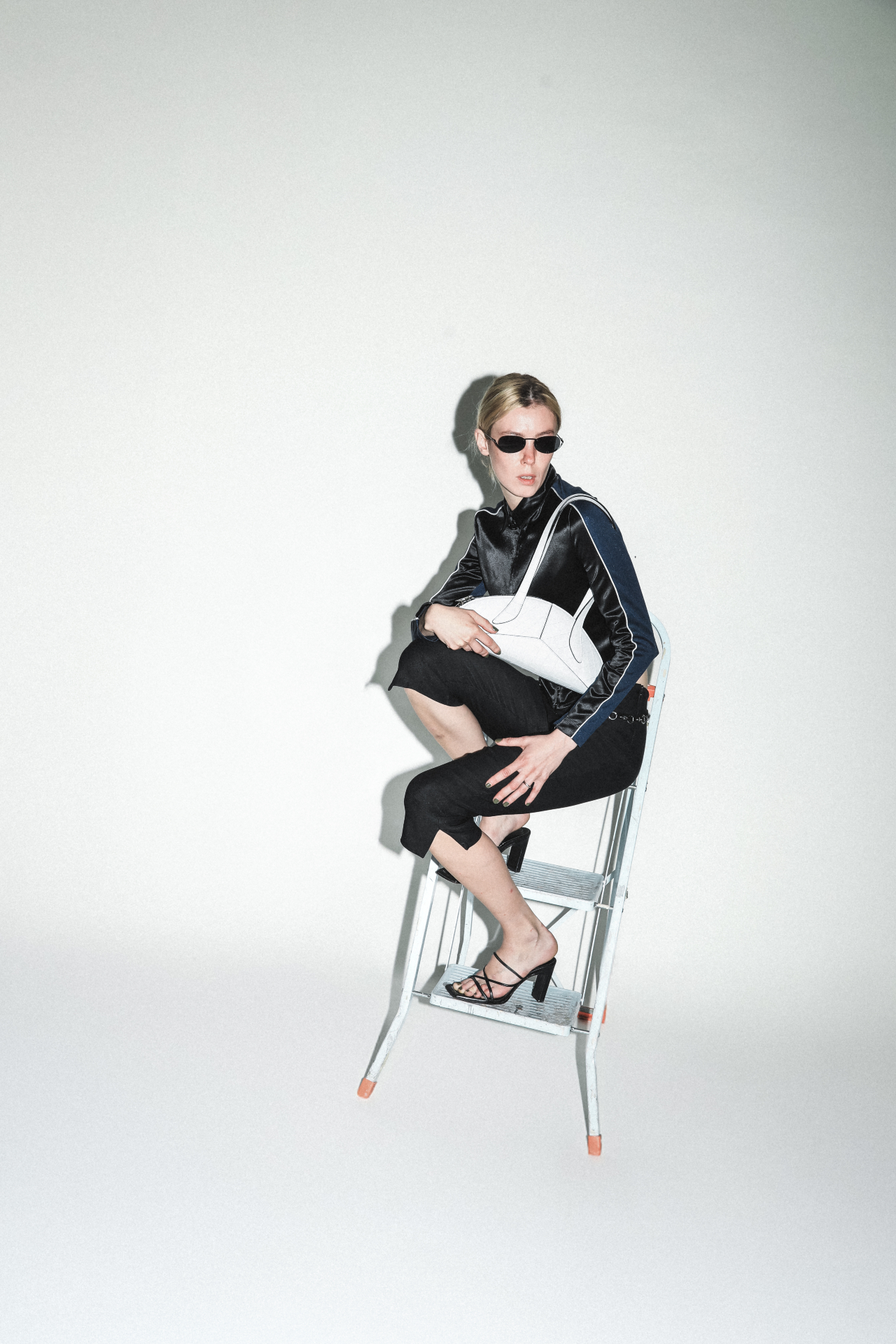 Model seated with a white structured bag