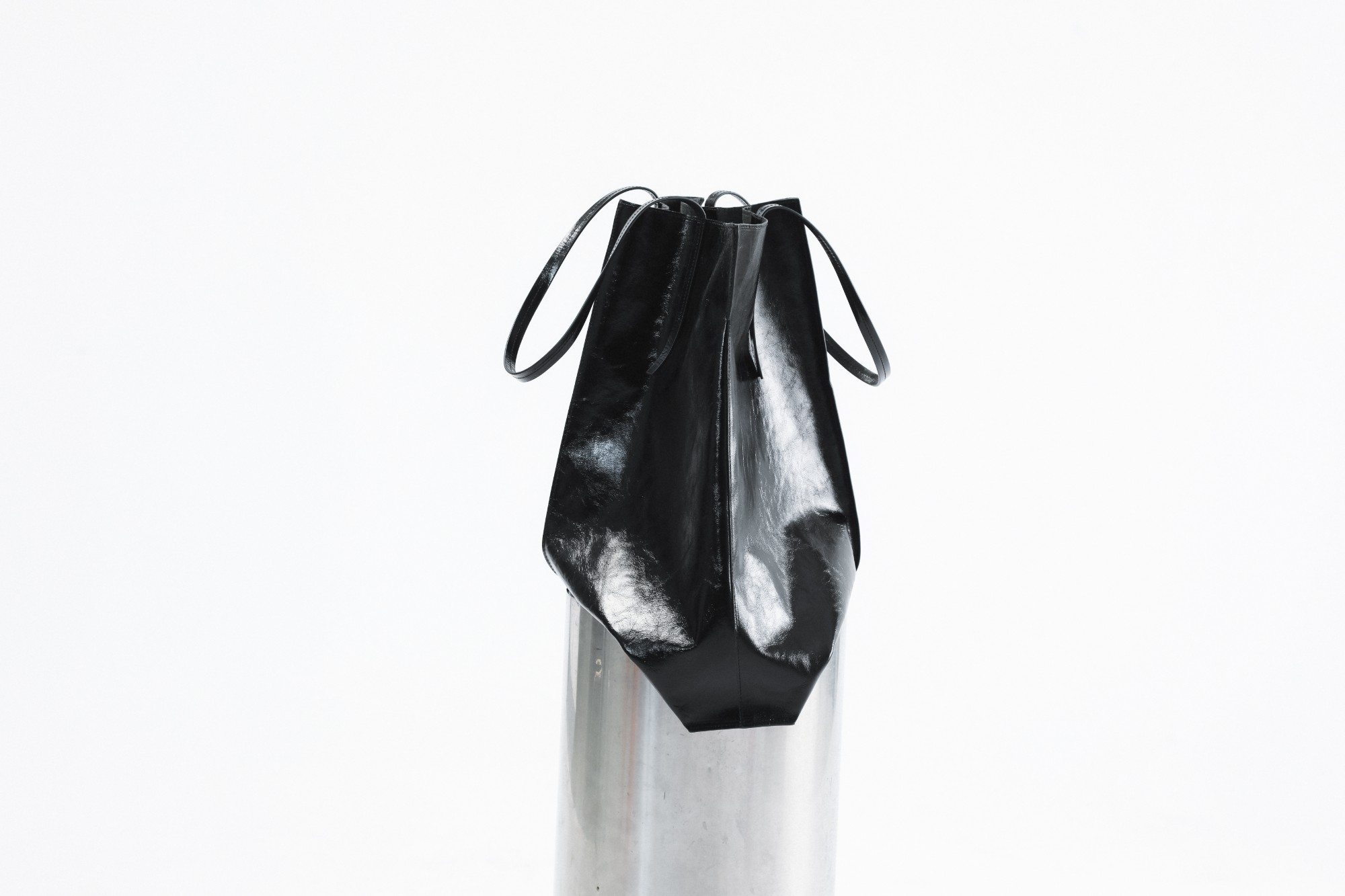 Black patent leather DIENÈE bag with looped handles on a steel column